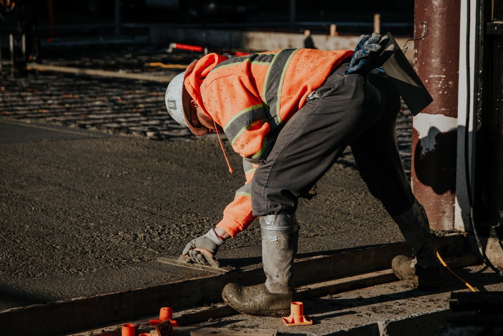 Un coffreur-bancheur lisse du béton sur un chantier